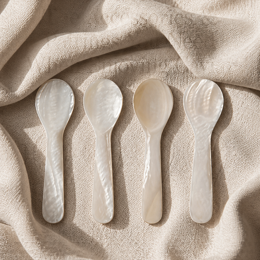 Four white ceramic spoons on a beige fabric background