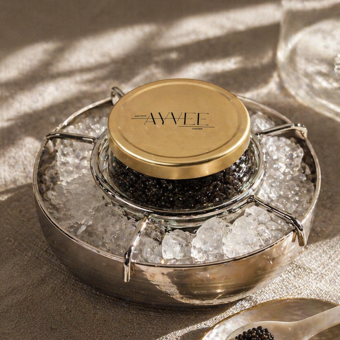 Jar of caviar with a gold lid on a textured surface, featuring the brand 'AYVEE'.